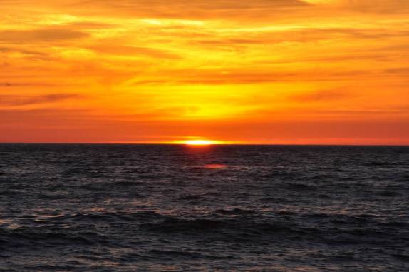 O sol se esconde atrás do Pacífico na praia central de Mazatlán, no México